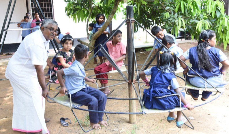 Shri D. Jacob, Chairman & Founder of Manovikas, with students at the school playground. - Photo